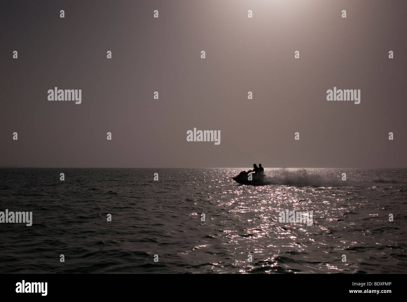 Silhouettes de deux hommes sur un jet ski au coucher du soleil. Banque D'Images