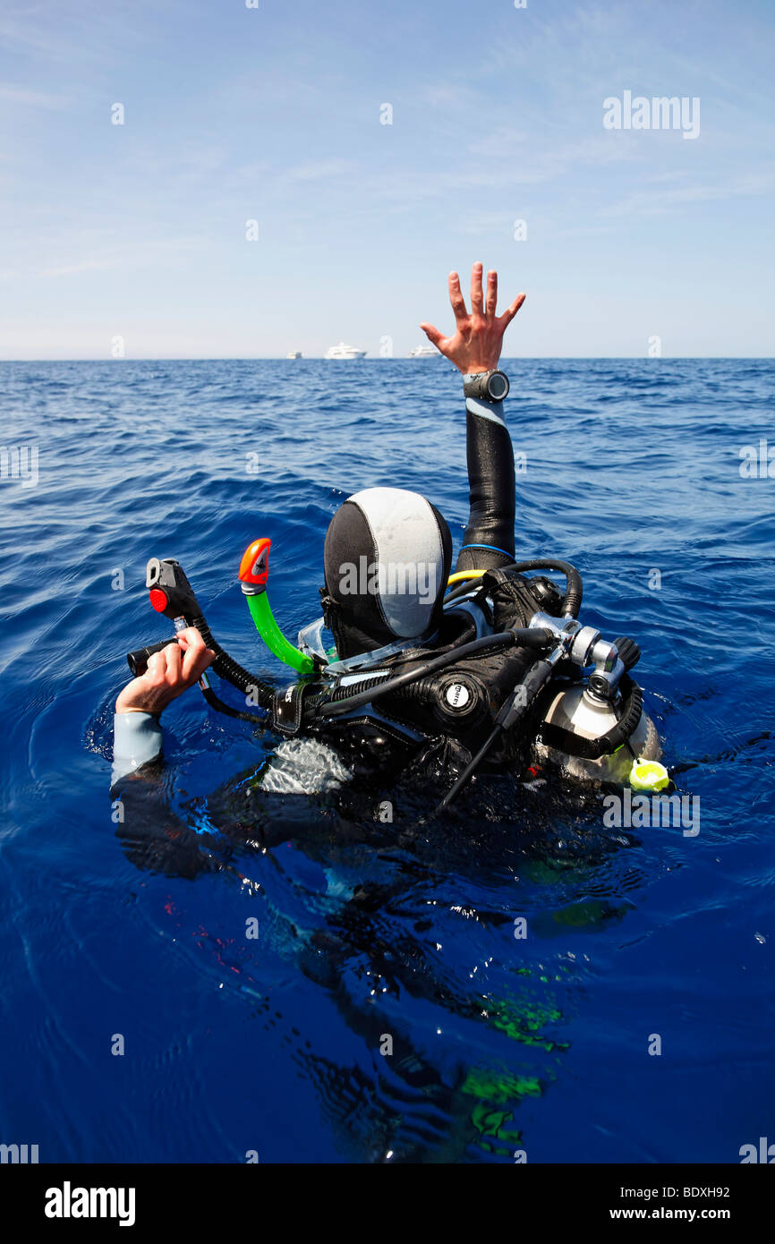 Plongeur à la dérive en mer tente d'obtenir l'attention des gens sur les bateaux de plongée à l'horizon avec un signal-corne et en agitant, Egyp Banque D'Images
