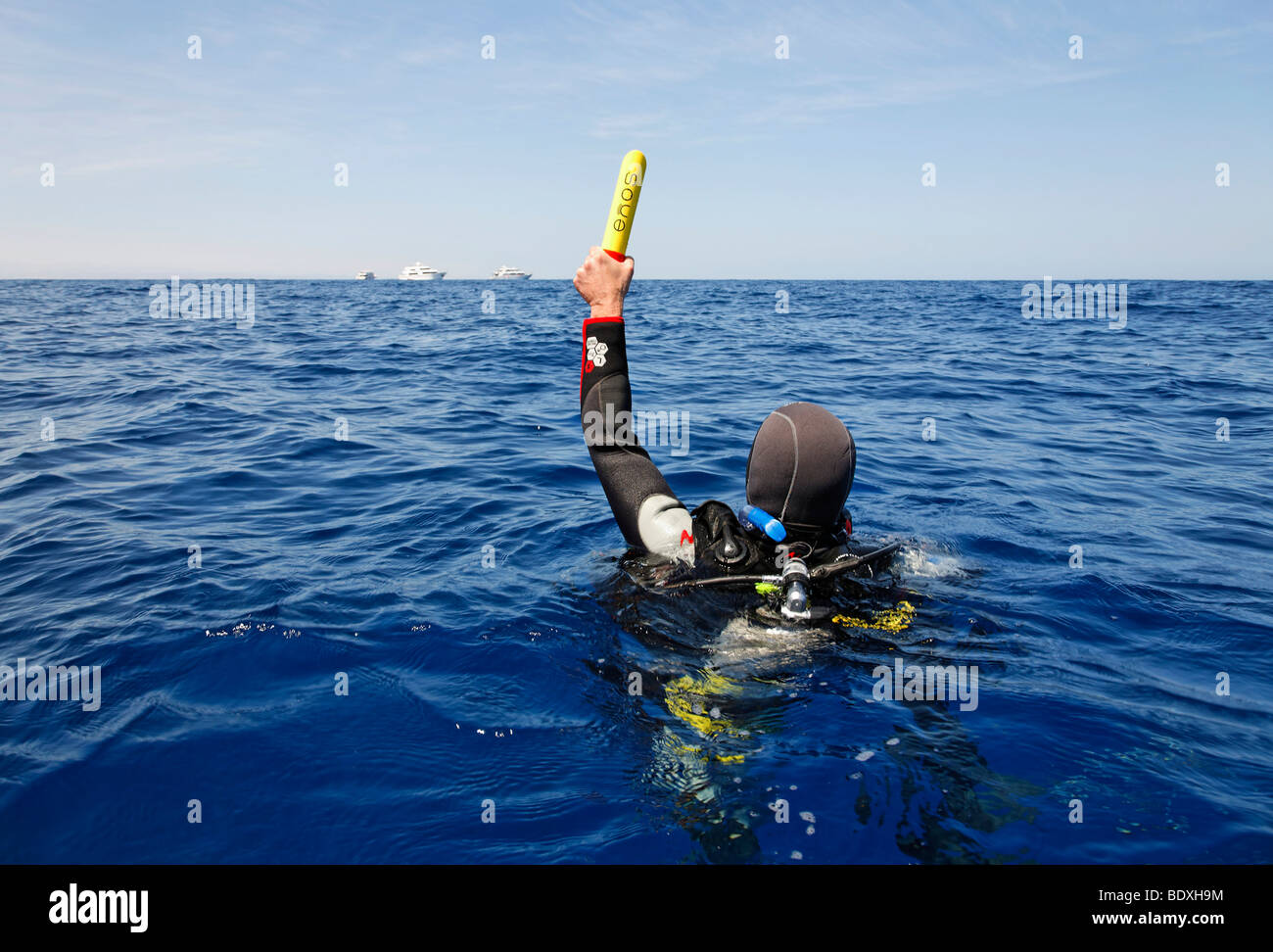 Plongeur à la dérive en mer tenant un émetteur ENOS, une alarme d'urgence électronique et système de repérage, au-dessus du niveau de l'eau, so Banque D'Images