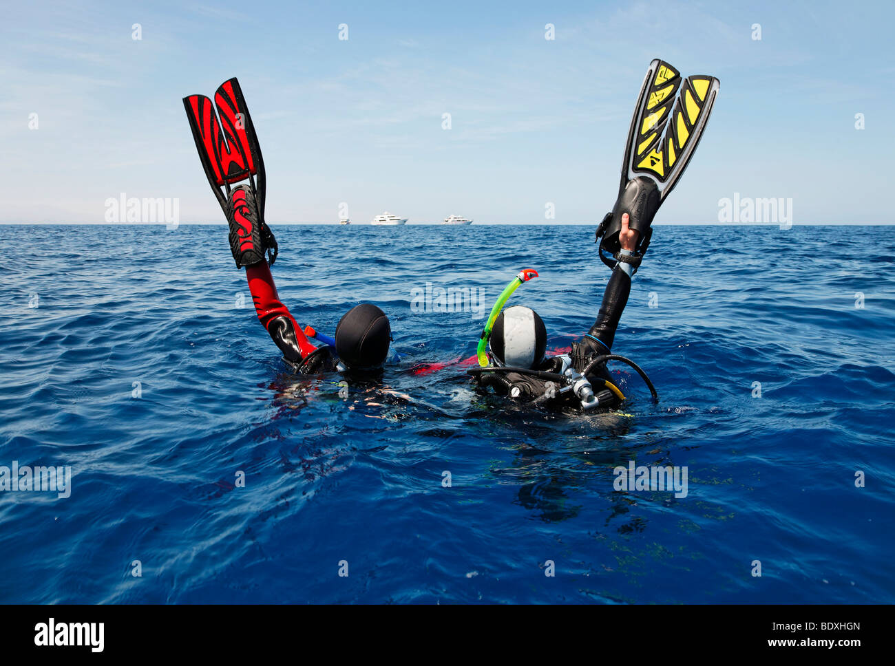 Les plongeurs à la dérive en mer s'efforcent d'obtenir l'attention des gens sur les bateaux de plongée sur l'horizon en l'agitant avec leurs palmes de plongée, Banque D'Images