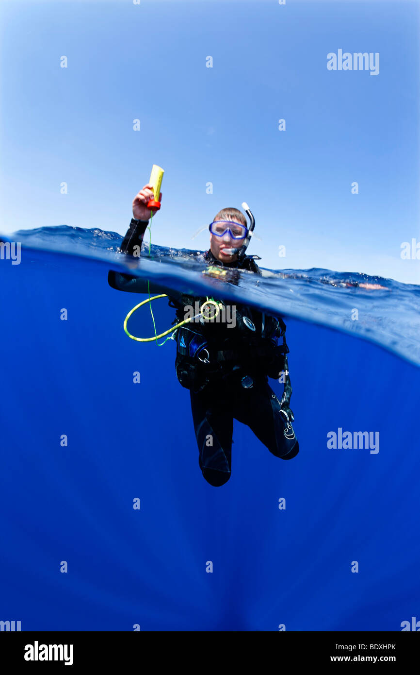 Plongeur à la dérive en mer la tenue d'un émetteur ENOS, une alarme d'urgence électronique et système de repérage, au-dessus du niveau de l'eau, so Banque D'Images