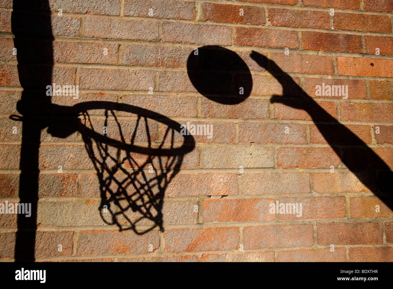 Un terrain de basket ball cerceau et jeter une ombre sur un mur de briques Banque D'Images