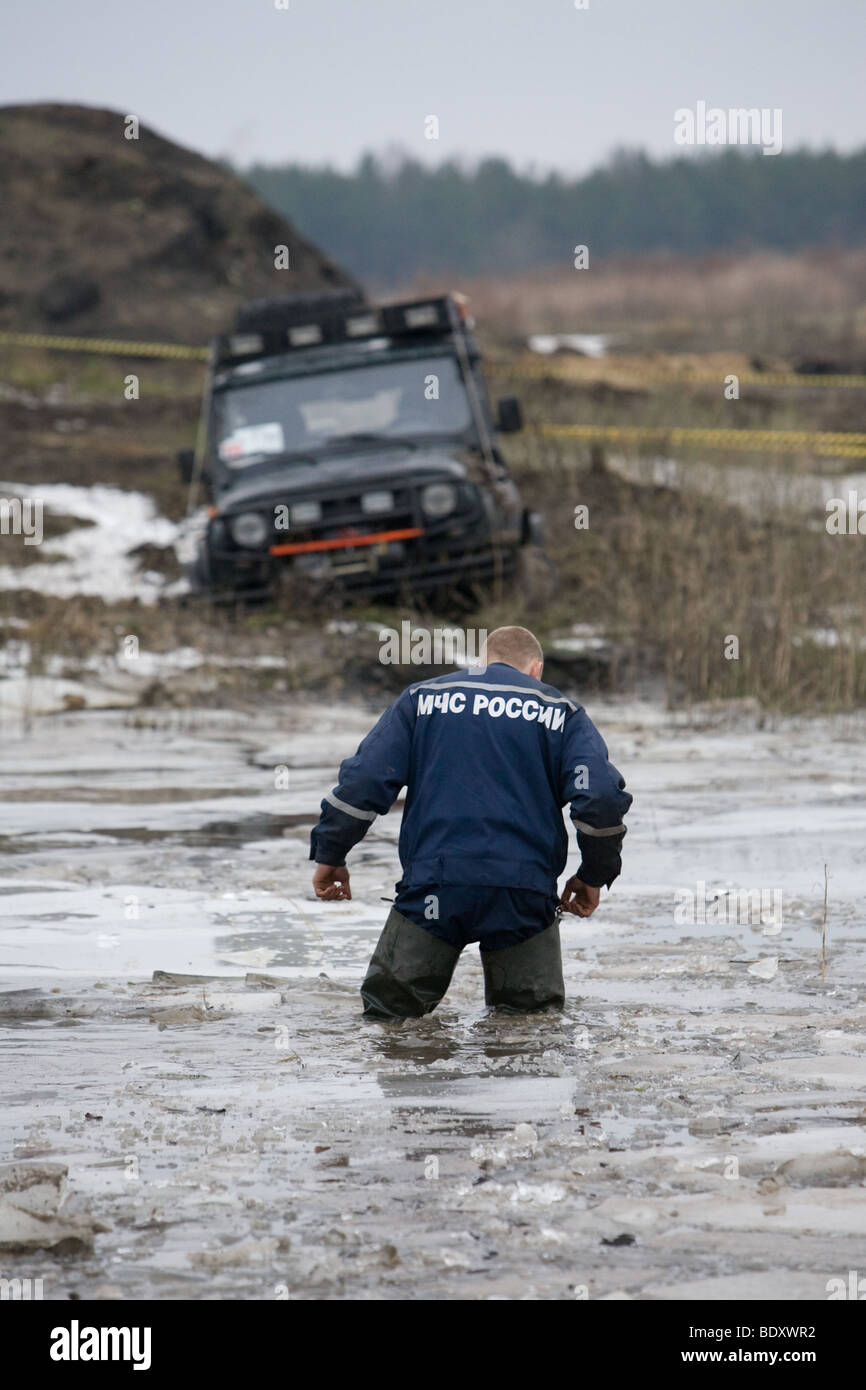 Stand sauveteur russe dans l'eau froide à proximité de voiture s'est coincé Banque D'Images