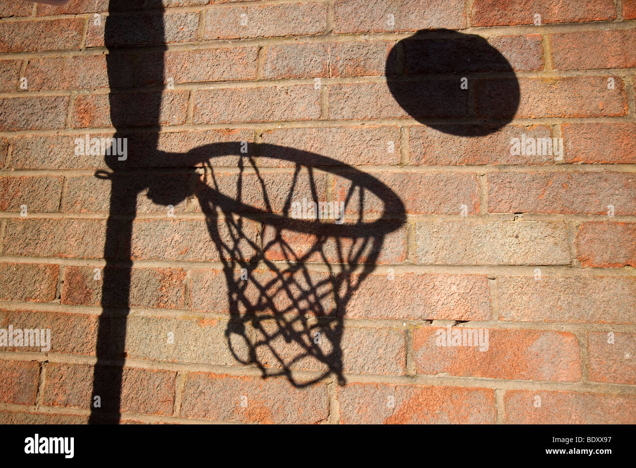 Un terrain de basket ball cerceau et jeter une ombre sur un mur de briques Banque D'Images