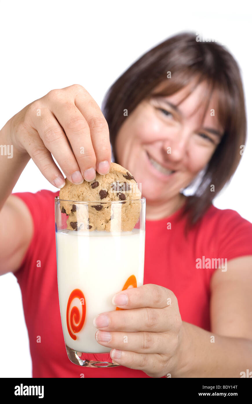 Heureusement une femme dunks son biscuit aux brisures de chocolat dans un verre de lait. Banque D'Images
