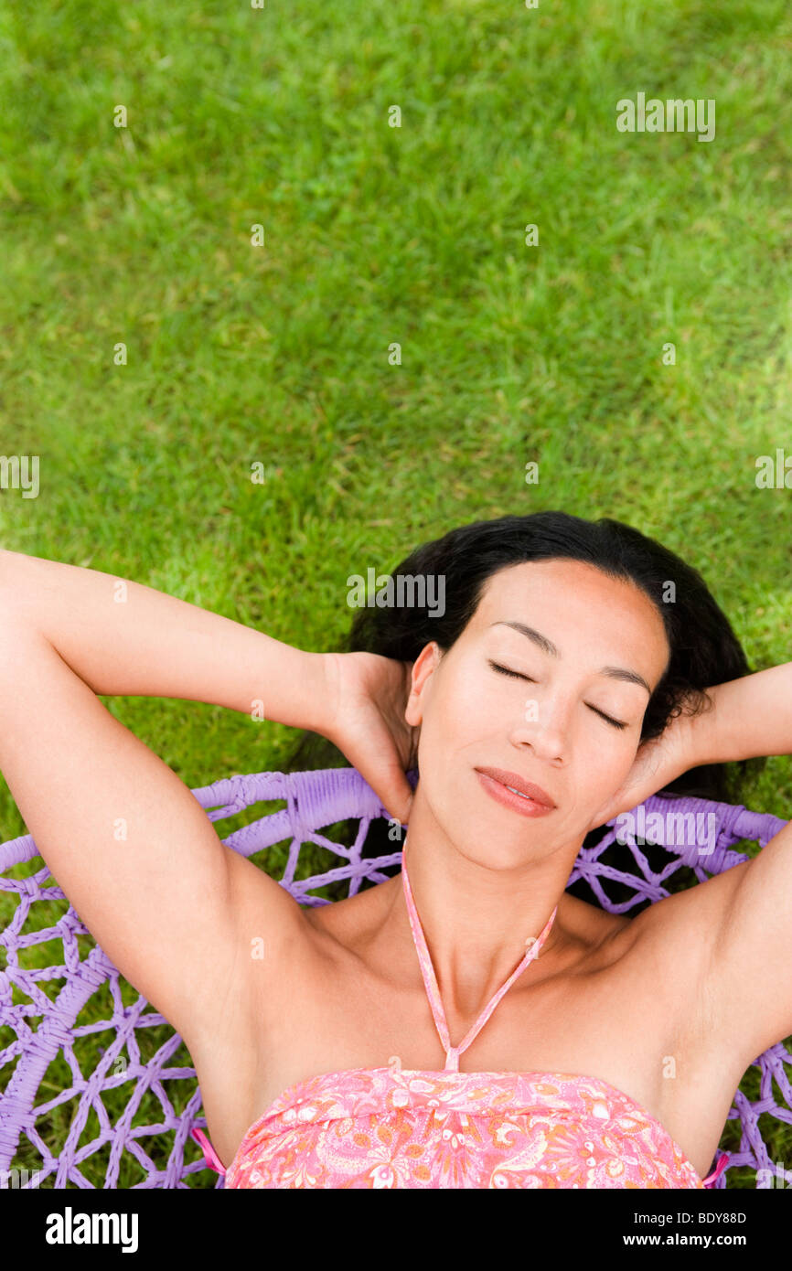 Woman relaxing in a swing les yeux fermés Banque D'Images