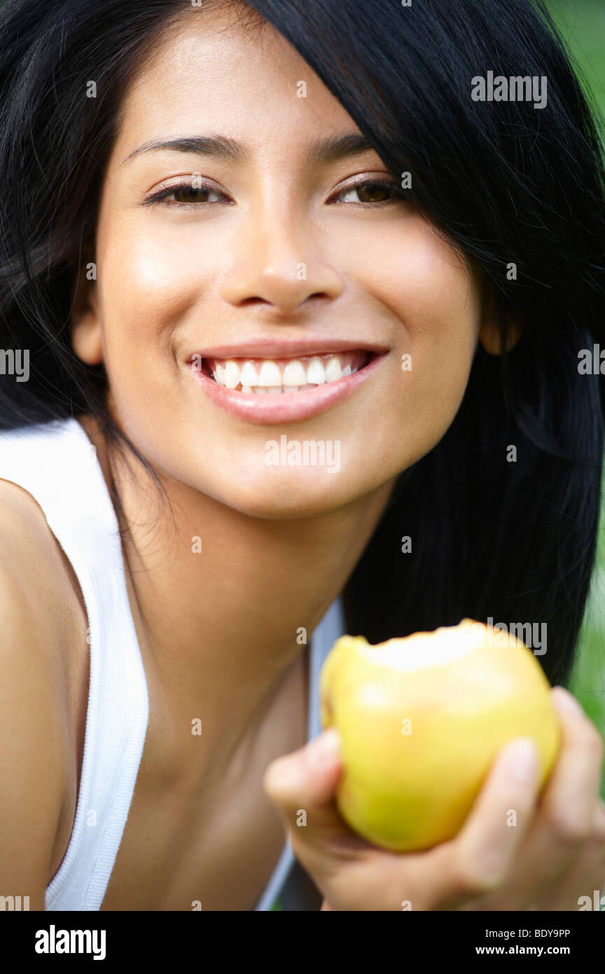 Femme de manger une pomme, smiling Banque D'Images