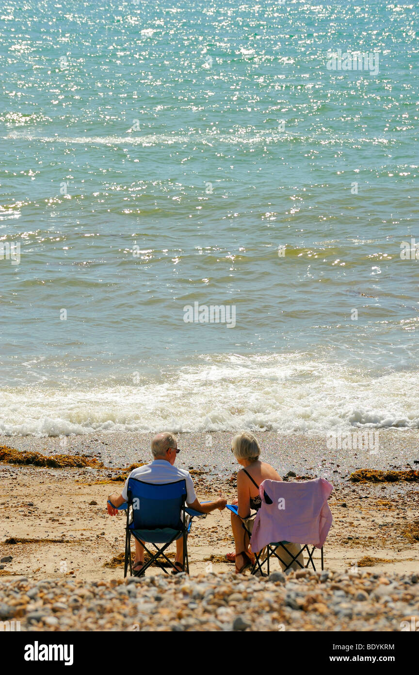 Tiré d'un vieux couple assis sur des chaises sur une plage Banque D'Images