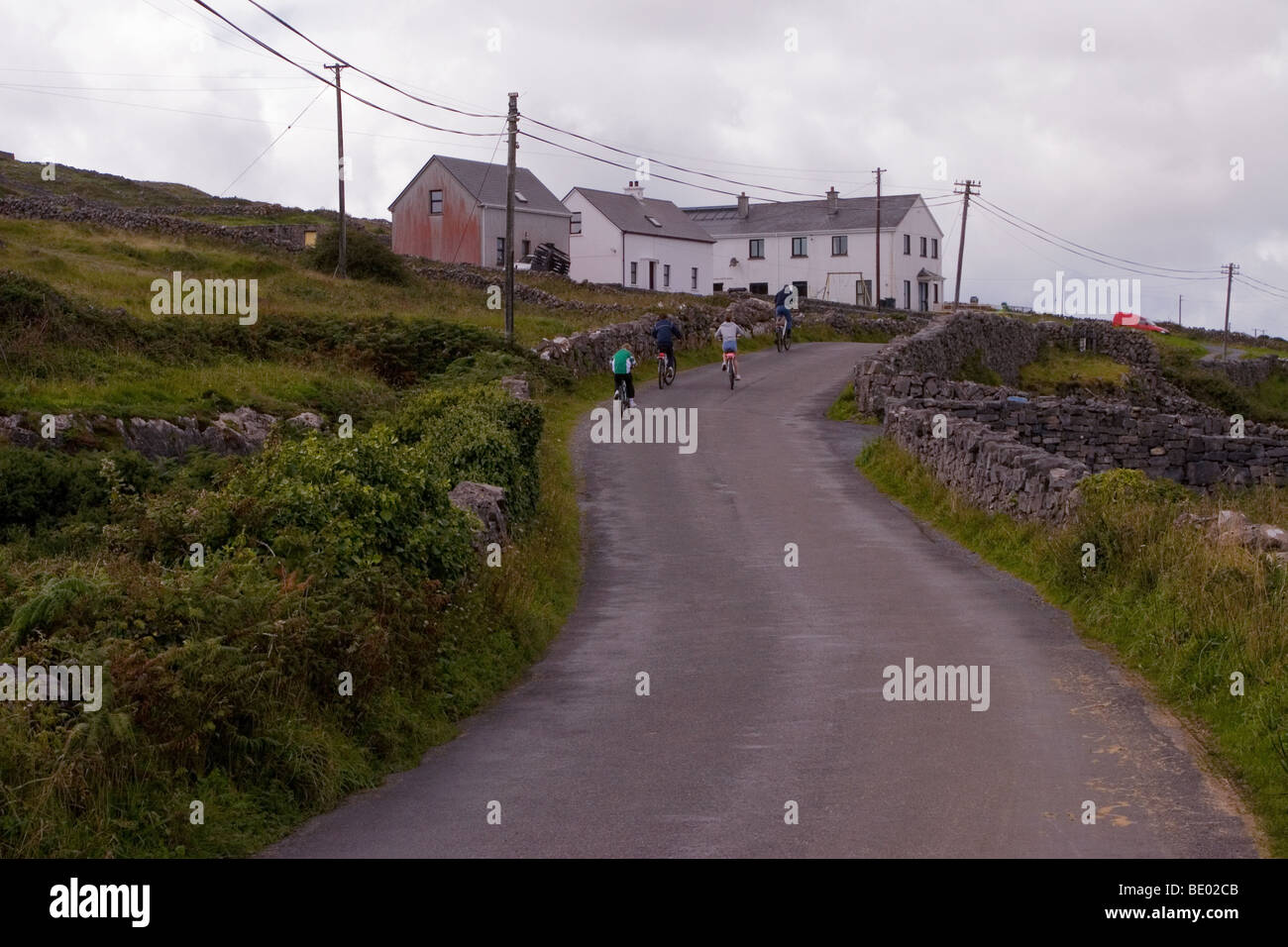Circuit à vélo en famille sur pays-route bordée de murs en pierre traditionnels, l'Inis Mor (Inismore) Island, les îles d'Aran, Co. de Galway, Irlande Banque D'Images