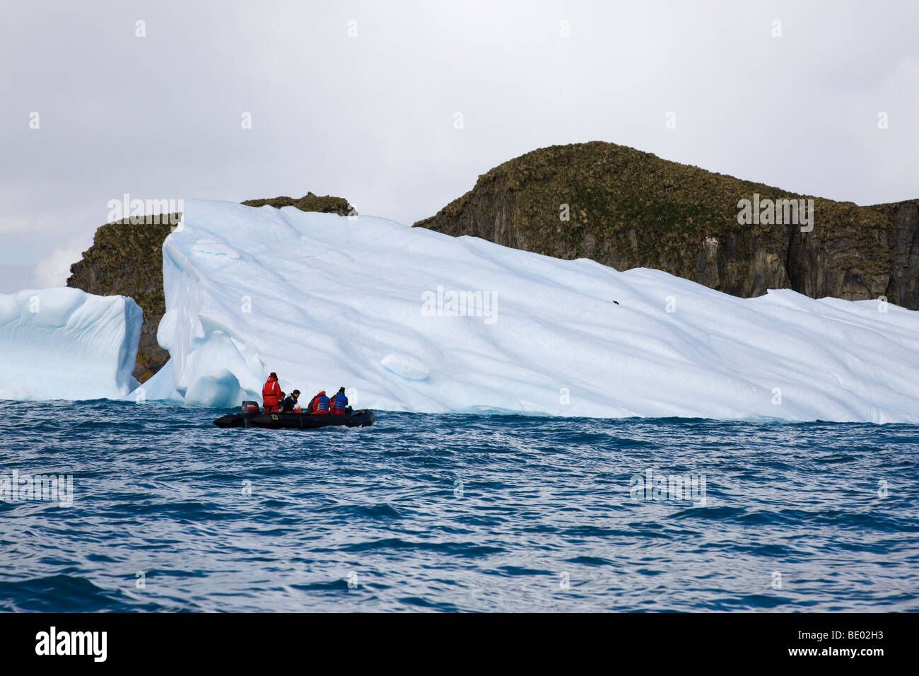 Petit bateau gonflable zodiac et passagers de croisière Explorer gros iceberg bleu flottant, la Géorgie du Sud, l'Antarctique, l'Antarctique Banque D'Images