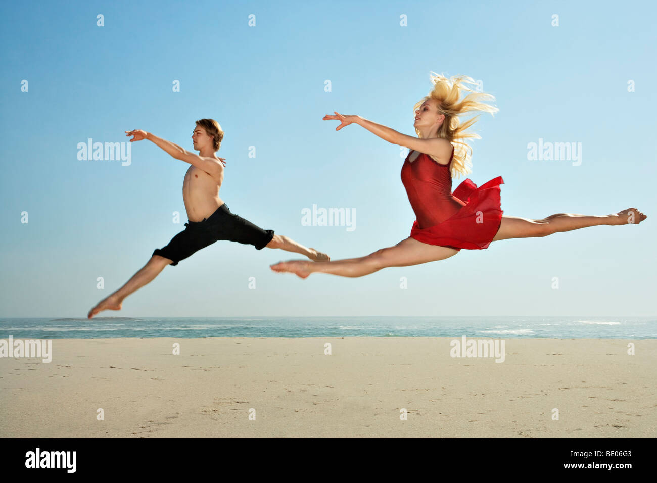 Danseurs sautant sur une plage Banque D'Images