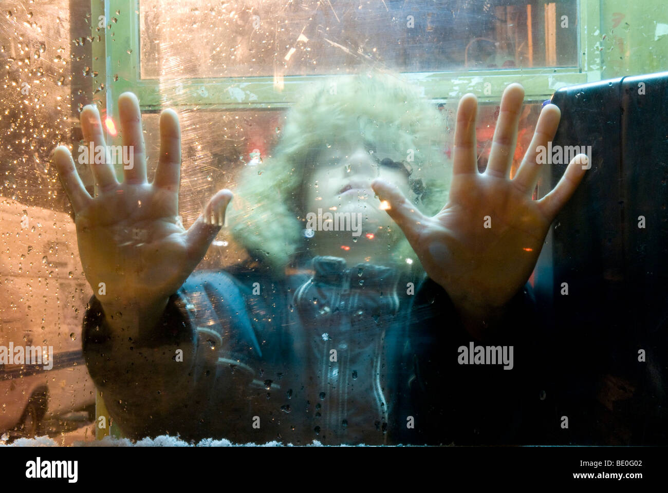 Avec les mains de l'enfant appuyé contre la fenêtre d'hiver Banque D'Images