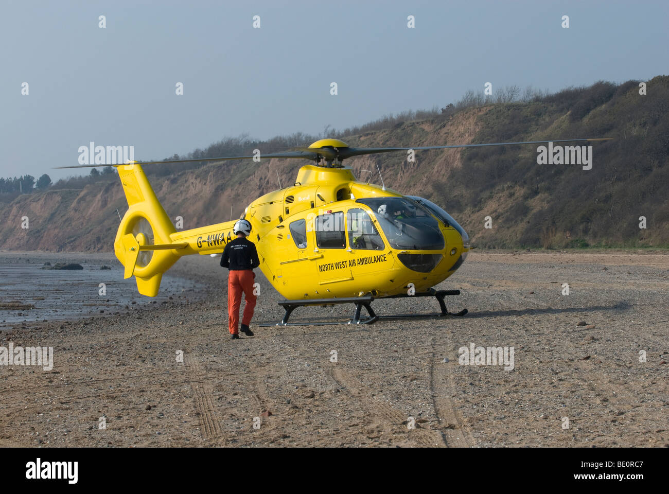 North West Air Ambulance G-NWAA hélicoptère avec pilote jaune on beach Banque D'Images