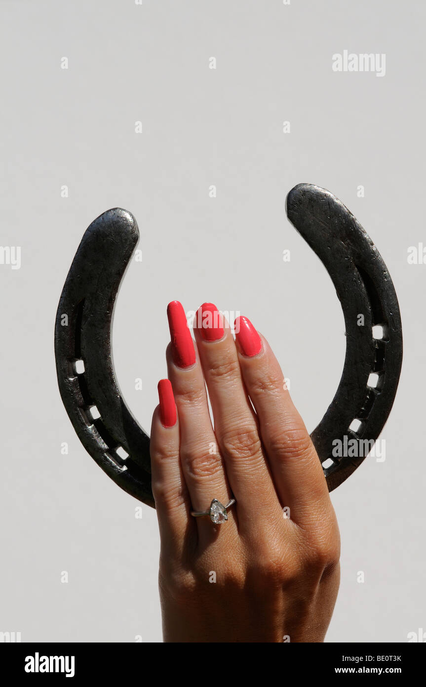 Woman's hand holding vernis à ongles rouge avec un vieux fer à cheval Photo  Stock - Alamy