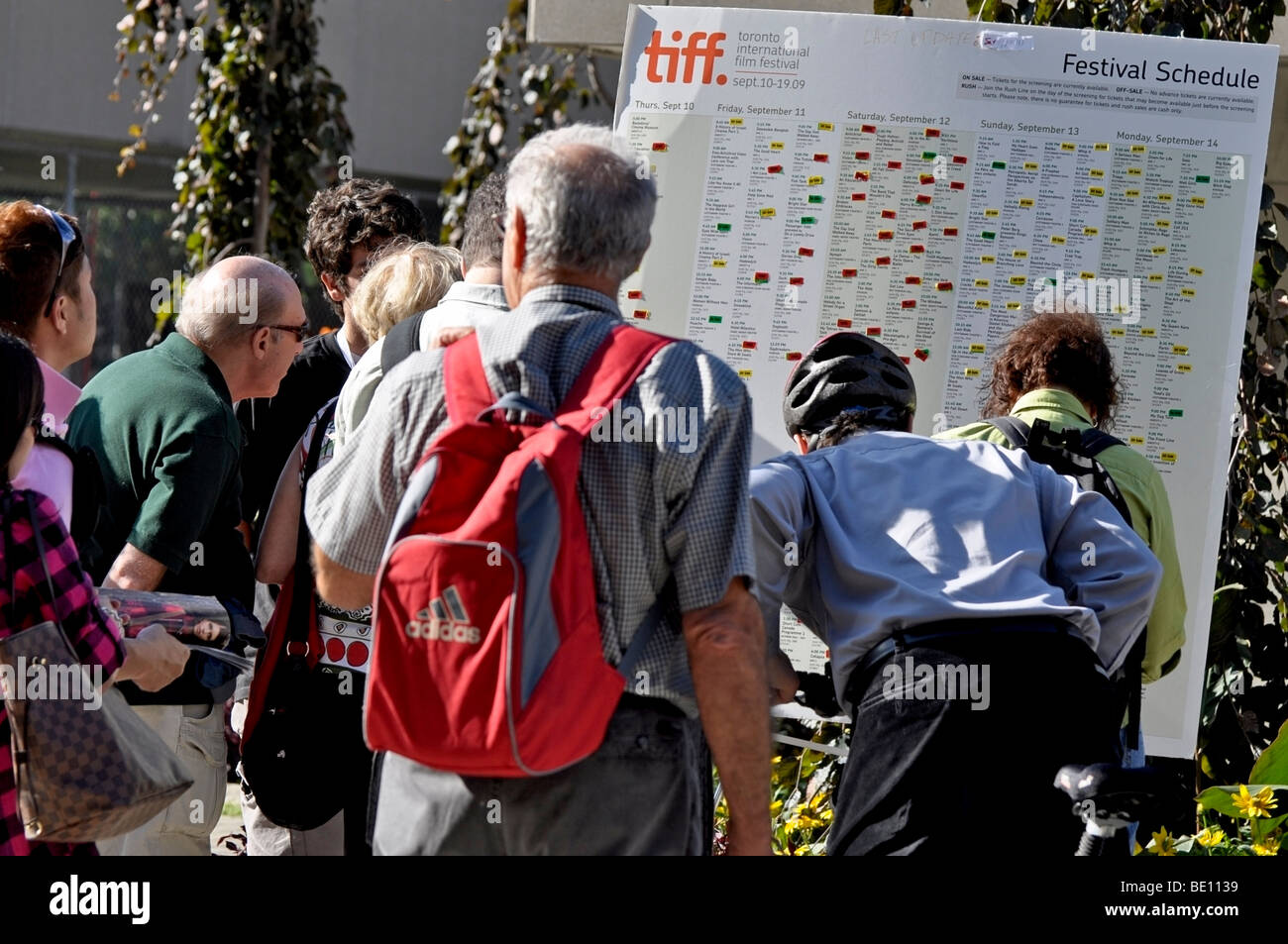 Les gens, les passants en étudiant le TIFF (Toronto International Film Festival les horaires) Banque D'Images
