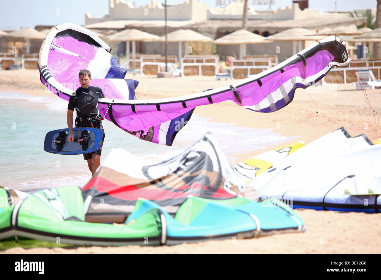 Kiteboarder marche dans le beach holding son cerf-volant. Banque D'Images