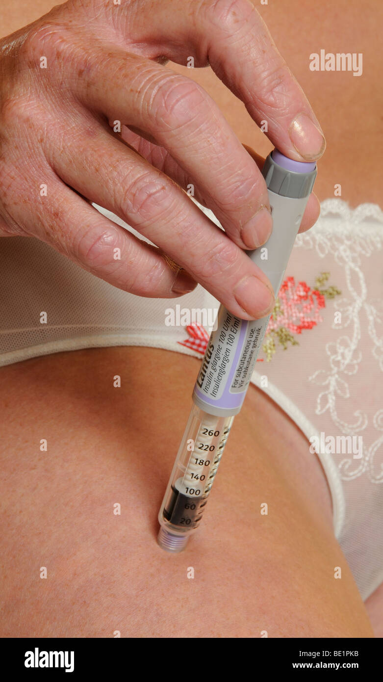 Femme à l'aide d'un stylo à insuline à injecter dans le haut de la jambe pour le diabète Banque D'Images