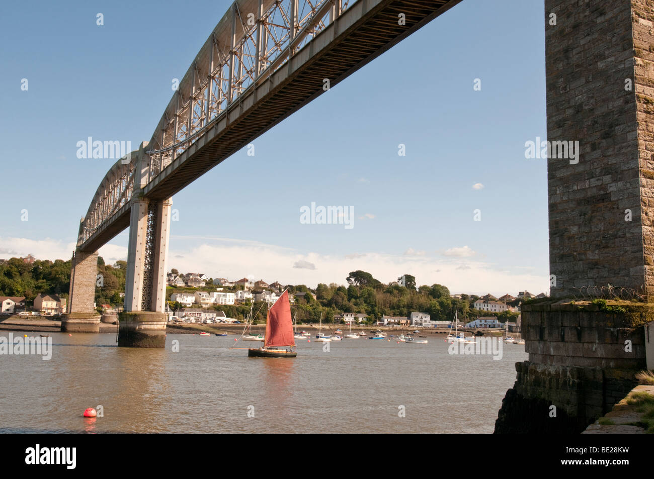 Sur la frontière de Devon et de Cornouailles un bateau à voile passe sous le Royal Albert Bridge sur la Rivière Tamar. Banque D'Images