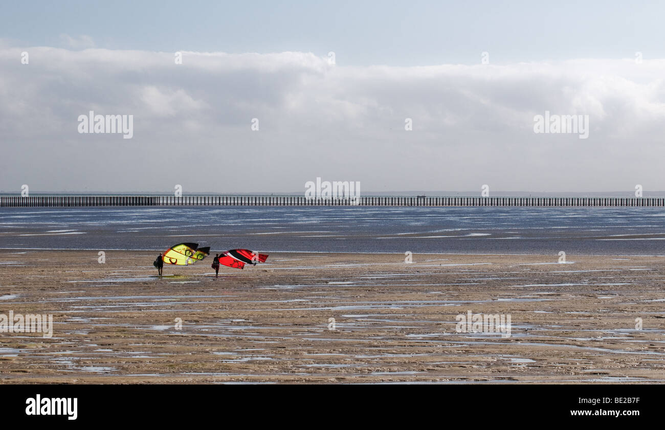 À marée basse, deux parasurfers portent leur passé à pied des parapentes Shoebury la rampe à l'estuaire de la Tamise. Photo par Gordon 1928 Banque D'Images