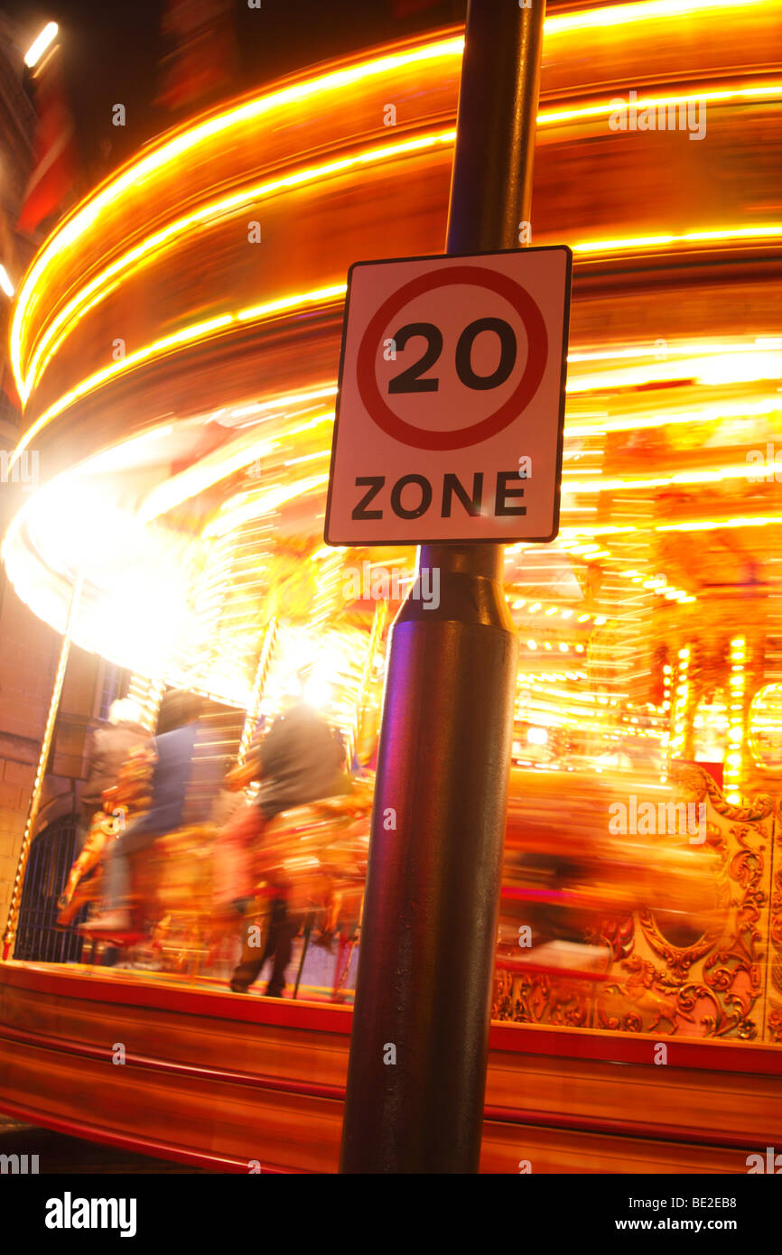 Signe de la limite de vitesse et l'exposition 'long' de filage carousel fairground ride illuminé la nuit, 'St Giles' fête foraine, Oxford, UK Banque D'Images