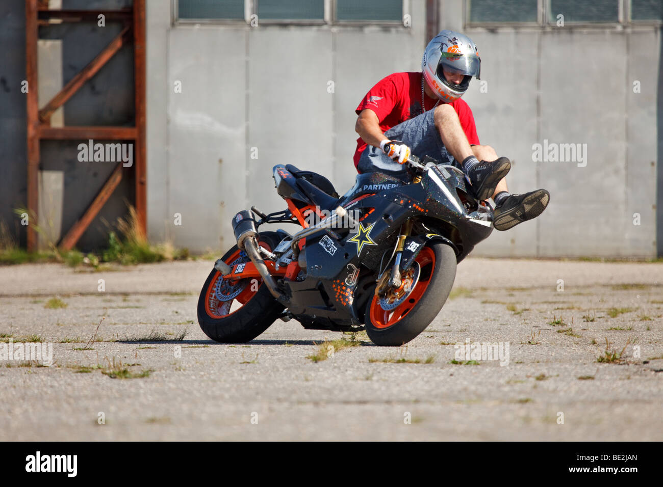 Stunt rider riding bike tout en gardant ses jambes sur le guidon Banque D'Images
