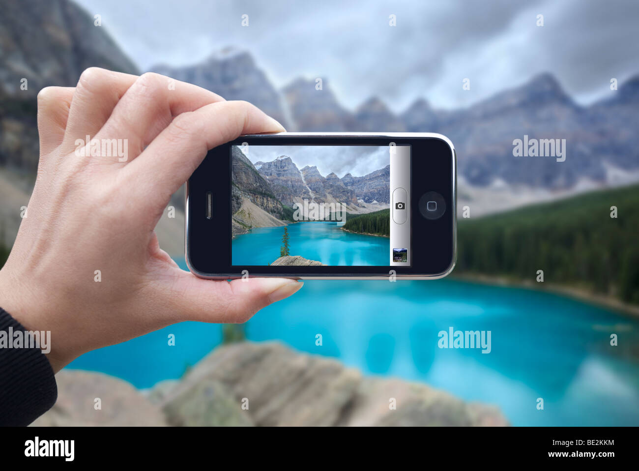 Woman tienne son iphone 3gs prendre photo de Moraine Lake en Alberta, Canada Banque D'Images