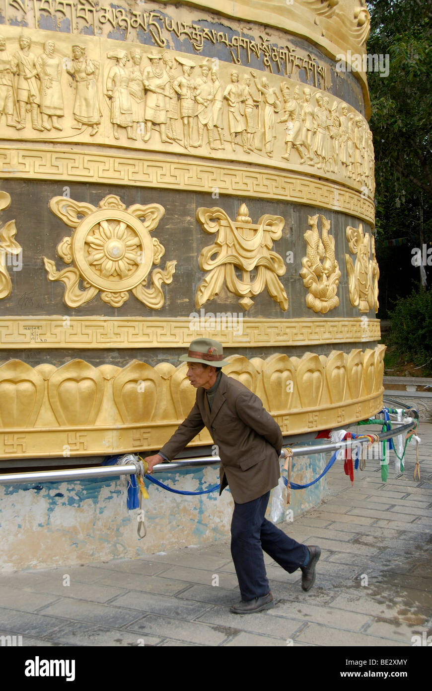 Le bouddhisme tibétain, le Tibétain, l'homme croyant tourner un moulin à prières géant, Zhongdian, Shangri-La, Yunnan Province Banque D'Images