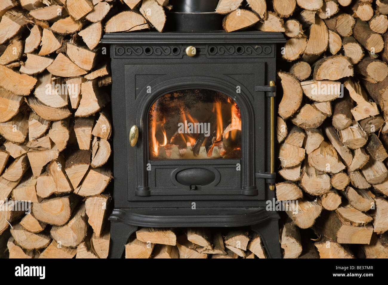 Poêle à bois entouré de bois empilés et haché prêt pour la gravure Banque D'Images