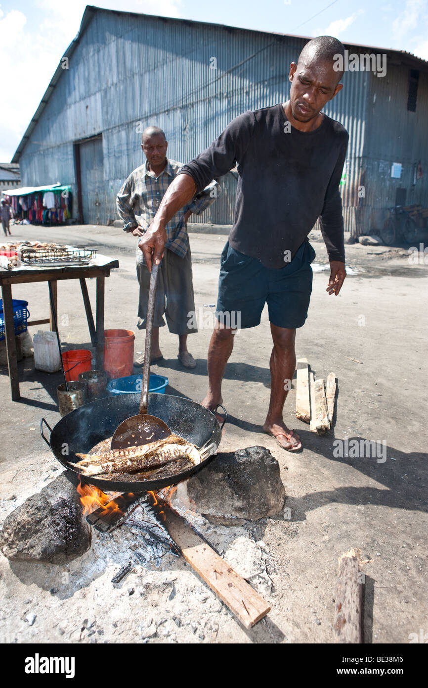 L'homme est un poisson à la cuisson au grilloir cookshop, Stonetown, Stone Town, Zanzibar, Tanzania, Africa Banque D'Images