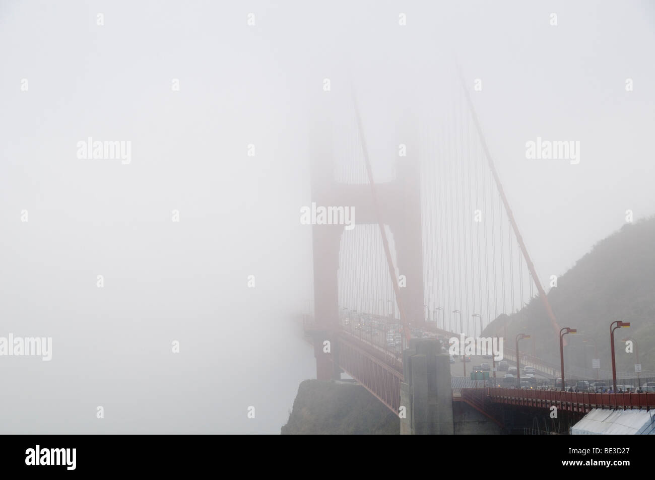 Trafic du Golden Gate Bridge partiellement obscurci par le brouillard San Francisco Californie // SAN FRANCISCO, Californie, États-Unis — le Golden Gate Bridge, dont le trafic est visible sur son pont, est partiellement obscurci par un brouillard dense lorsqu'il s'étend à travers la baie de San Francisco. Ce pont suspendu emblématique, achevé en 1937, est célèbre pour sa couleur orange internationale distinctive et son design Art déco. Il est considéré comme une merveille d'ingénierie significative du XXe siècle. La travée principale du pont mesure 1 280 mètres (4 200 pieds) et sa longueur totale est de 2 737 mètres (8 981 pieds). Il relie la ville de Banque D'Images