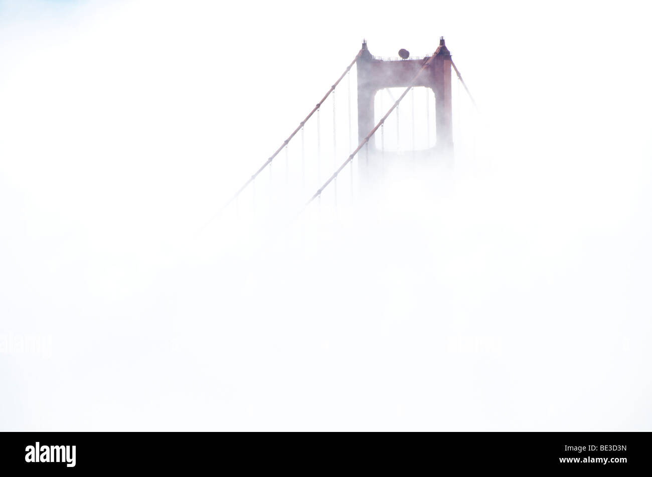 Golden Gate Bridge Tower in Fog San Francisco California USA // SAN FRANCISCO, California — Une tour du Golden Gate Bridge, un pont suspendu, est partiellement obscurcie par le brouillard sur la baie de San Francisco. Achevé en 1937, le pont est reconnu pour son design Art déco distinctif. Il relie la ville de San Francisco au comté de Marin, enjambant le détroit du Golden Gate. Sa construction a été une réalisation remarquable de l'ingénierie, surmontant des conditions difficiles. La couleur Orange internationale du pont a été choisie pour améliorer sa visibilité par temps brumeux. Banque D'Images