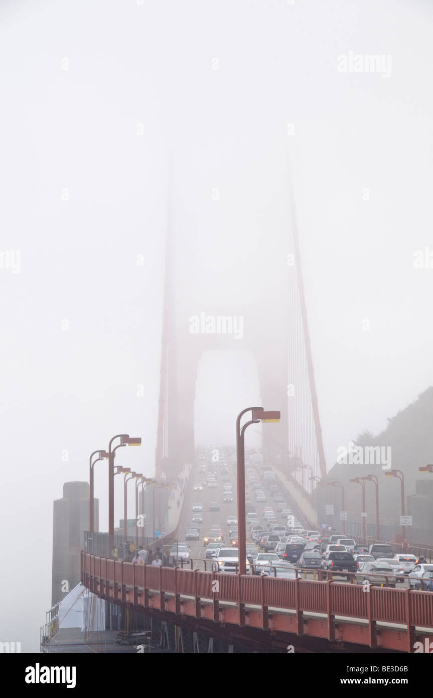 Pont du Golden Gate piétons à trafic lourd brouillard San Francisco États-Unis // SAN FRANCISCO, Californie — le pont du Golden Gate est entouré d'un brouillard dense, avec des véhicules en trafic intense traversant sa travée et des piétons sur sa passerelle. Ce pont suspendu emblématique relie la ville de San Francisco au comté de Marin, enjambant le détroit du Golden Gate. Achevé en 1937, il s'agissait d'une réalisation d'ingénierie monumentale et de la plus longue travée de pont suspendu au monde à l'époque, mesurant 2,7 kilomètres (1,7 milles). Le pont est une artère de transport vitale et un symbole mondialement reconnu de San FR Banque D'Images