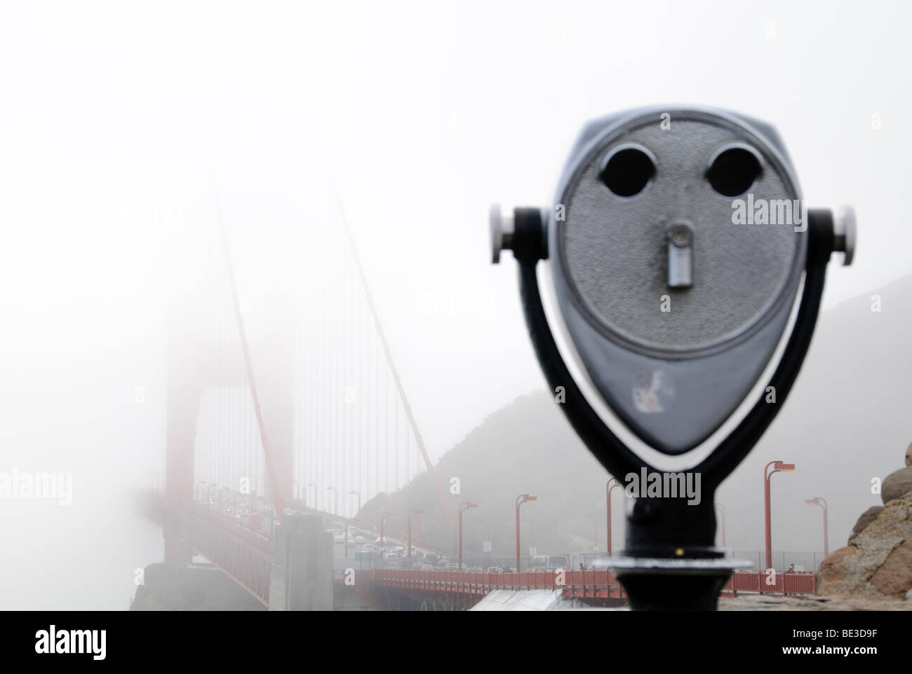 Golden Gate Bridge Fog coin Operated Telescope San Francisco Californie // SAN FRANCISCO, Californie — Un télescope à pièces est au premier plan, avec l'emblématique Golden Gate Bridge entouré d'un épais brouillard en arrière-plan. Les tours Orange internationales distinctives et les câbles suspendus du pont sont à peine visibles à travers l'épais brouillard. Le brouillard est une caractéristique atmosphérique commune à San Francisco, enveloppant souvent le pont et les zones environnantes. Ouvert en 1937, le Golden Gate Bridge est un pont suspendu de renommée mondiale reliant San Francisco au comté de Marin. C'est un transport vital Li Banque D'Images