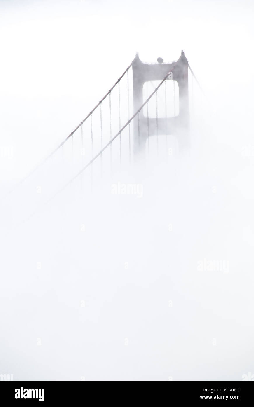 Golden Gate Bridge Tower in dense Fog San Francisco California // SAN FRANCISCO, California, États-Unis — le Golden Gate Bridge, un pont suspendu important de San Francisco, est partiellement obscurci par un brouillard dense. Cette structure emblématique enjambe le détroit du Golden Gate, reliant San Francisco au comté de Marin. Achevé en 1937, il est réputé pour sa couleur orange internationale distinctive, son design Art déco et son ingénierie monumentale. La travée principale du pont mesure 1 280 mètres (4 200 pieds) et ses tours s'élèvent à 227 mètres (746 pieds) au-dessus de l'eau. Il est largement considéré comme l'un des plus famo Banque D'Images