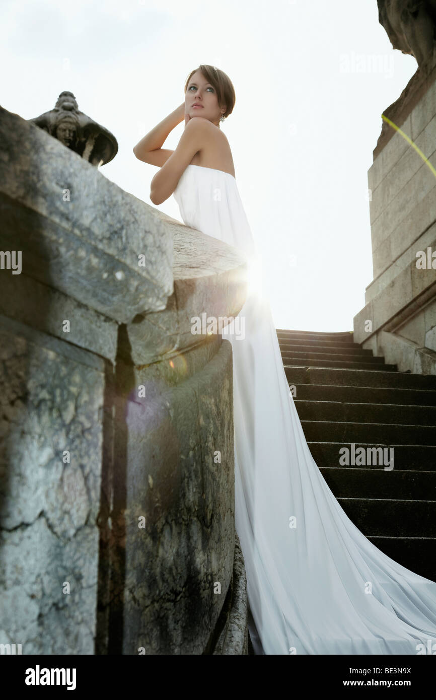 Photo de Mode d'une jeune femme blonde en robe blanche avec long train s'appuyant sur le garde-fou du pont Alexander, Pa Banque D'Images