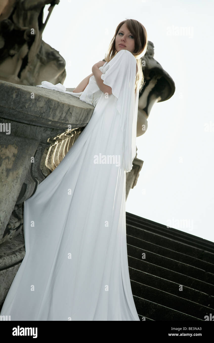 Photo de Mode d'une jeune femme blonde en robe blanche avec long train s'appuyant sur le garde-fou du pont Alexander, Pa Banque D'Images