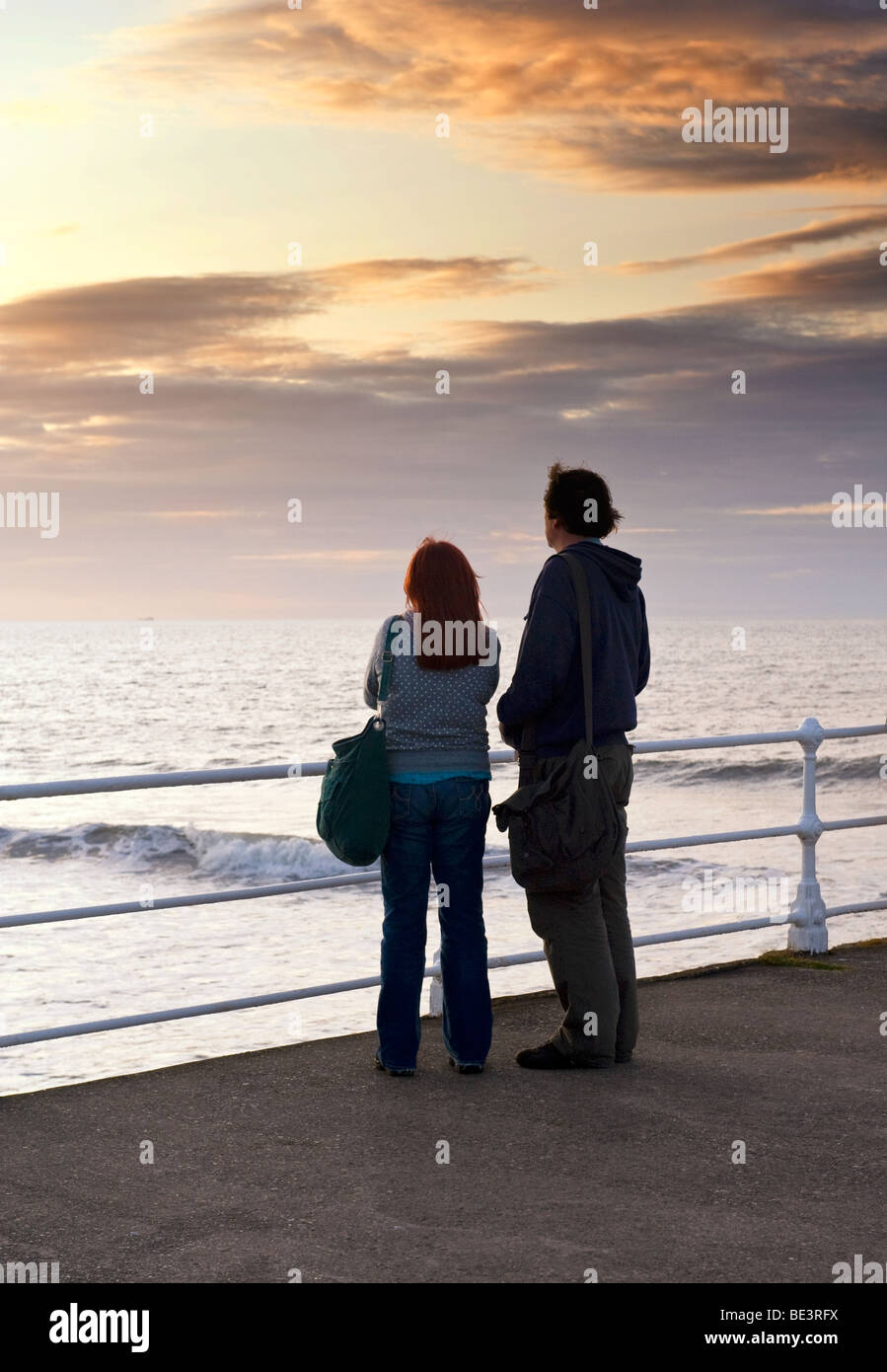 Couple se leva regardant le coucher de soleil sur la mer Banque D'Images