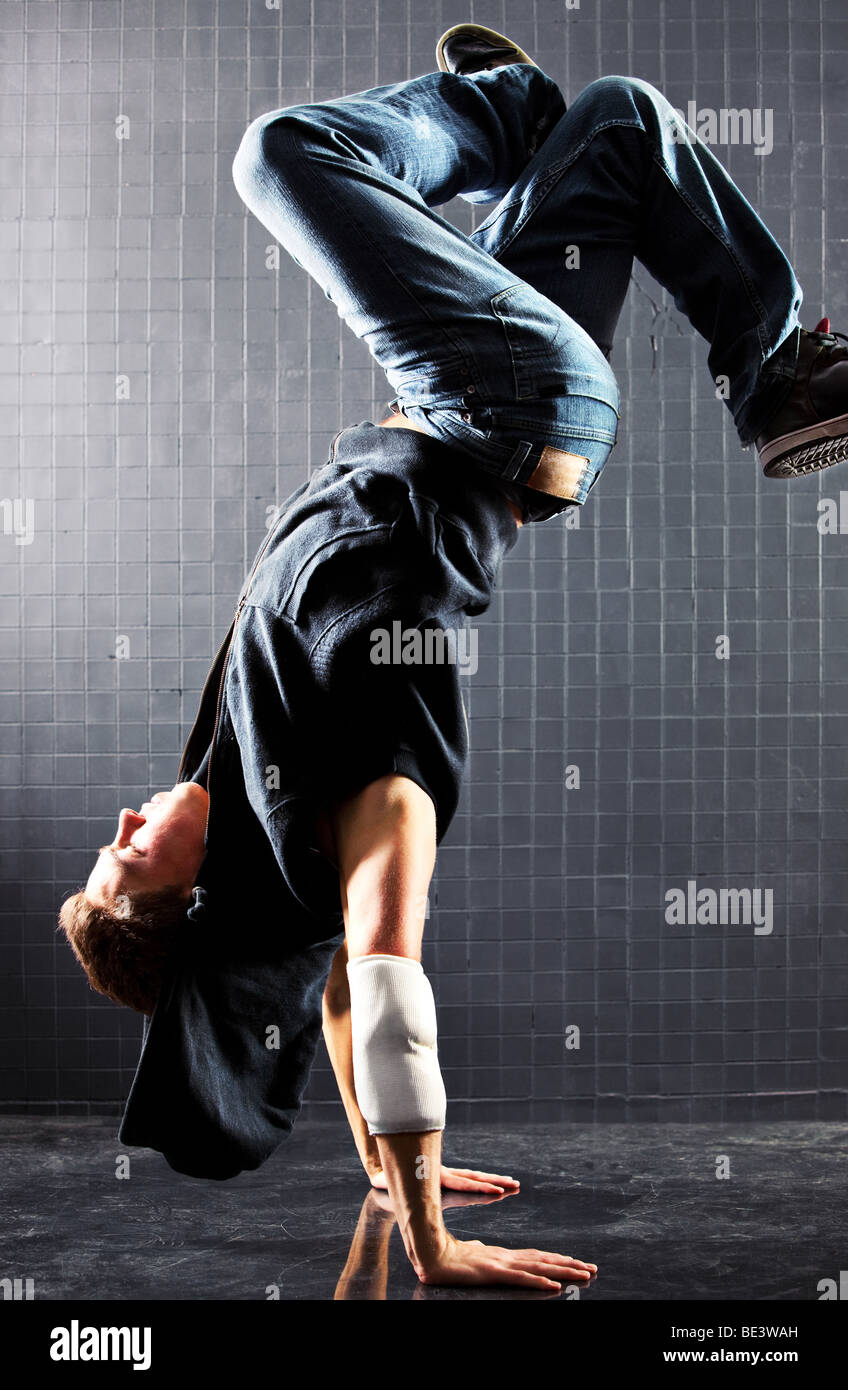 Jeune homme la danse moderne. Sur le mur sombre arrière-plan. Banque D'Images