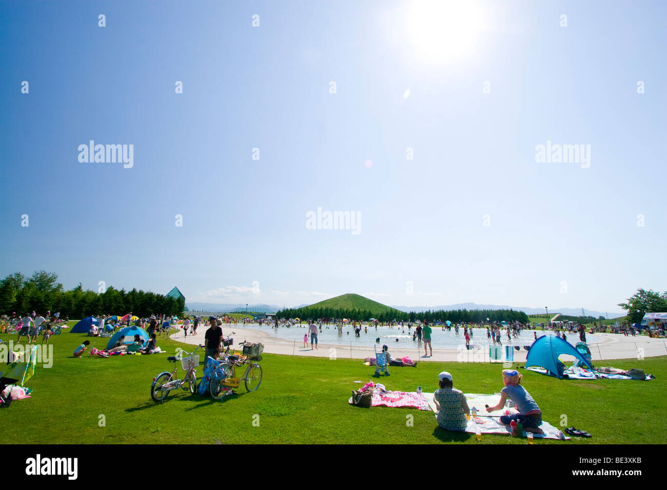 Les familles bénéficient d'un après-midi de printemps ensoleillé à côté d'une grande piscine au coeur de Moerenuma Park. Banque D'Images