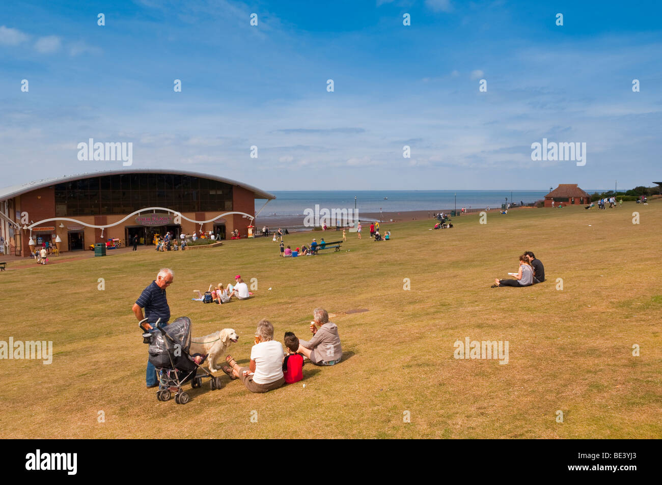 Les vacanciers assis sur le livre vert à la recherche sur la mer à Hunstanton , North Norfolk , Royaume-Uni Banque D'Images