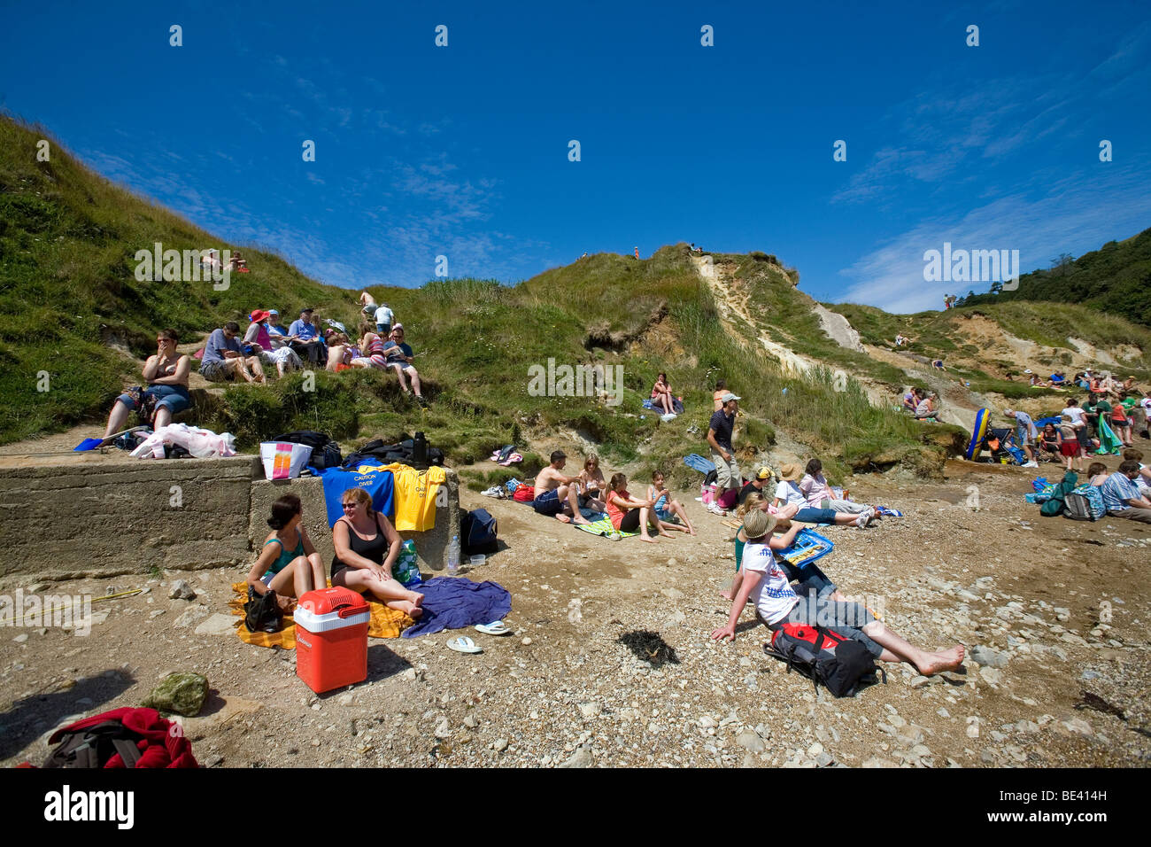 Les touristes appréciant le soleil de l'été sur la crique de Lulworth Cove Banque D'Images