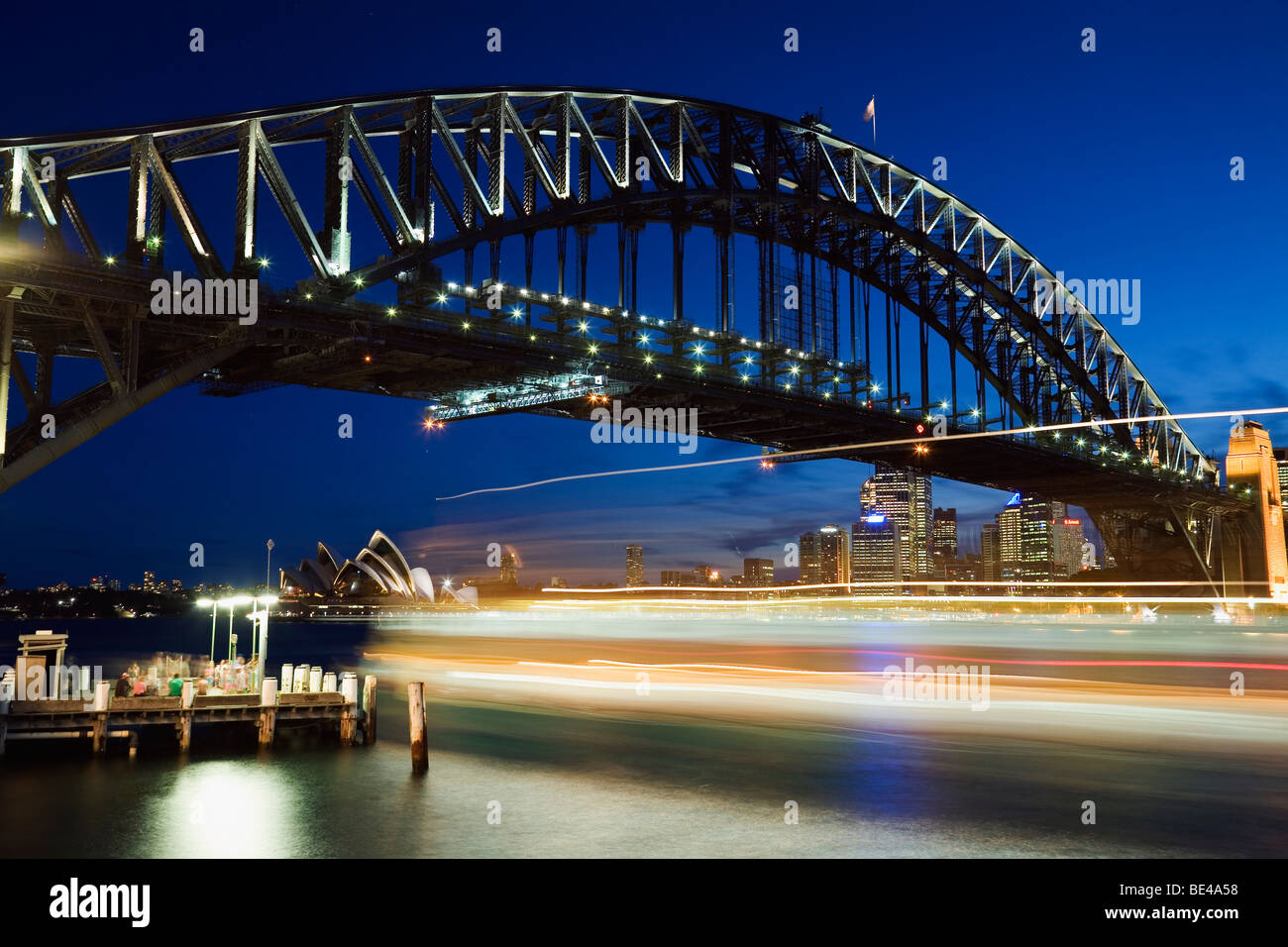 Les sentiers de la lumière d'un ferry sur le port de Sydney, avec le Harbour Bridge et l'Opéra. Sydney, New South Wales, Australia Banque D'Images