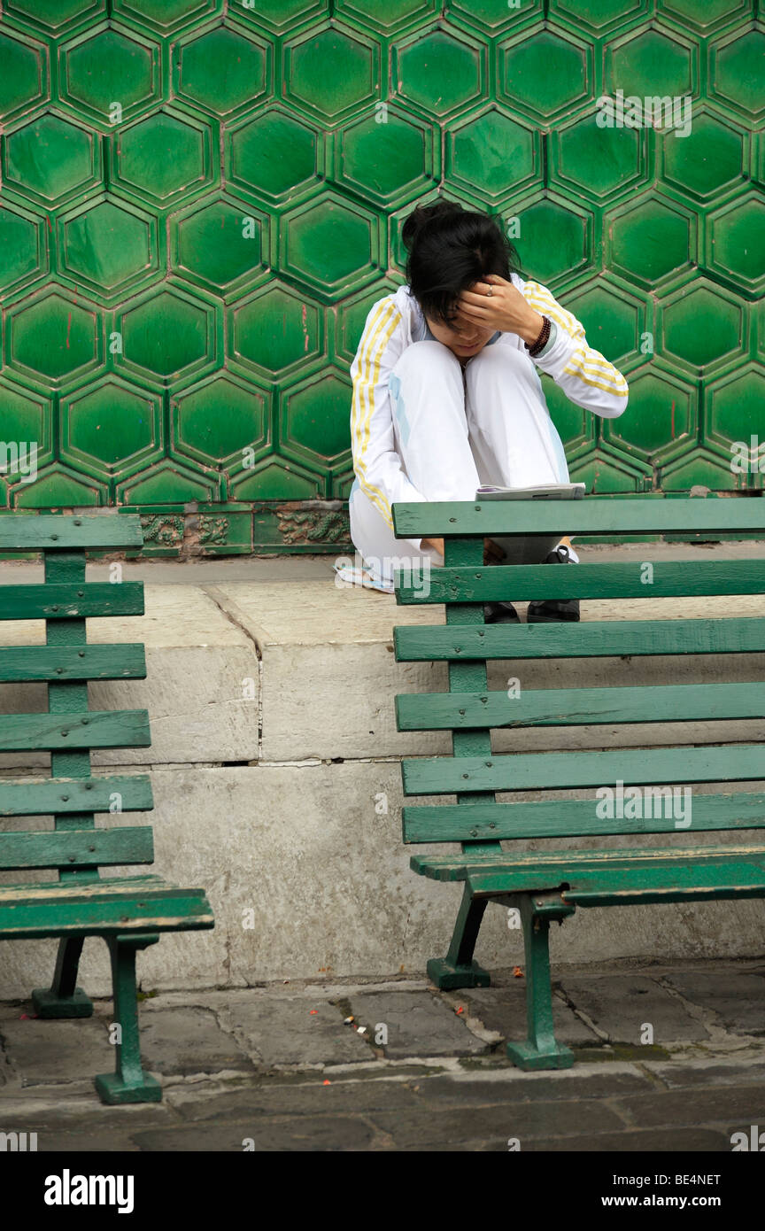 Une jeune femme lisant dans la cour de la Lama Temple Yonghe Gong, Beijing CN Banque D'Images