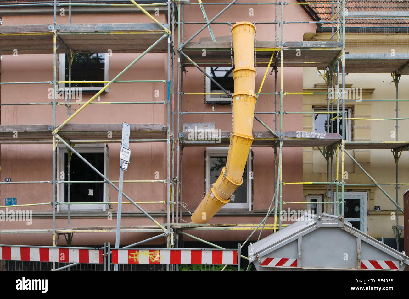 Maison échafaudée avec chute de débris, poubelles et marquages de sécurité Banque D'Images