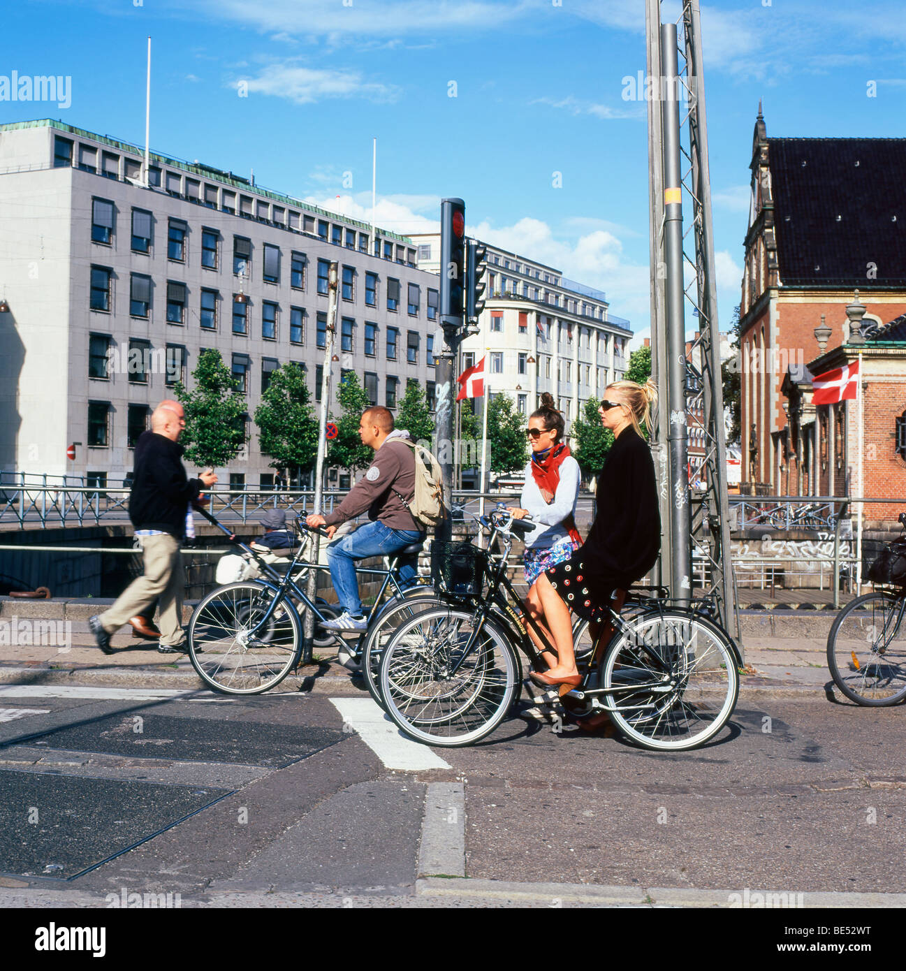 Femme élégante cycliste de banlieue en attente avec groupe de personnes sur des vélos sur une rue, à un carrefour en été à Copenhague Denmar KATHY DEWITT Banque D'Images