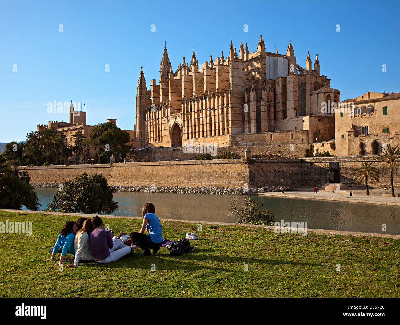 Groupe d'enfants assis sur l'herbe avec Cathedral Palma Majorque Banque D'Images