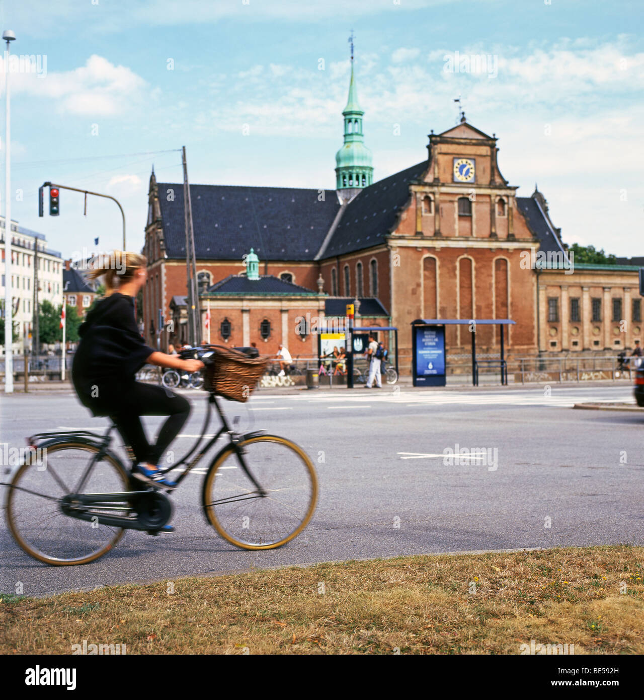 Une jeune femme d'une bicyclette avec un panier d'été passé en Borsgade bâtiment à Copenhague Danemark KATHY DEWITT Banque D'Images