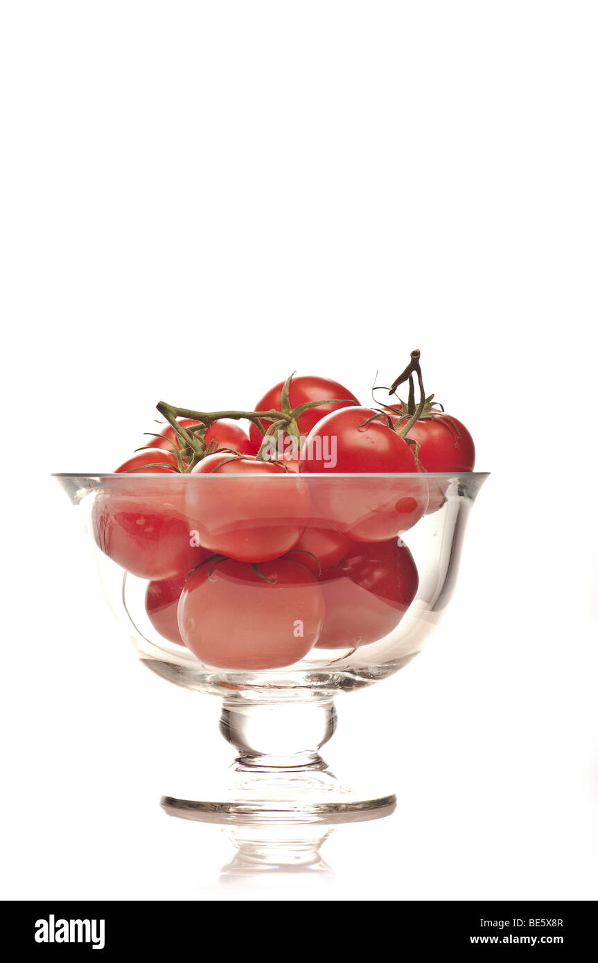 Les tomates biologiques sur la vigne dans un bol en verre contre un arrière-plan blanc découpe studio Banque D'Images