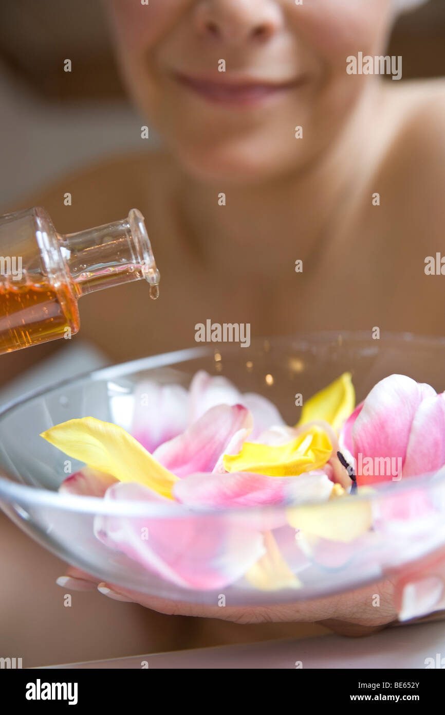 Le mélange additif de bain femme huile parfumée et fleurs Banque D'Images