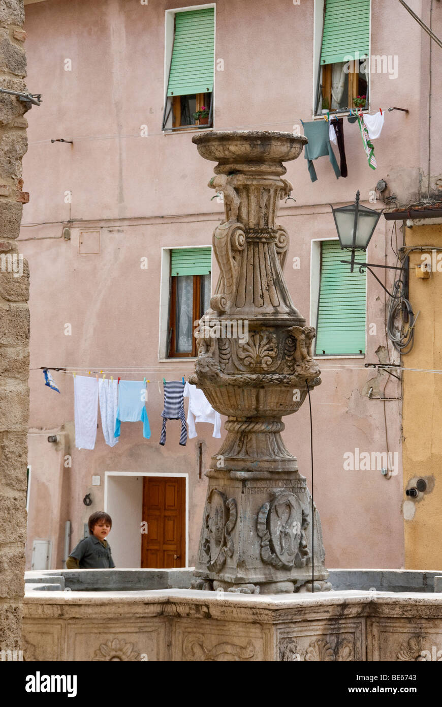 Garçon italien près d'une fontaine dans la ville de Sienne Asciano Banque D'Images